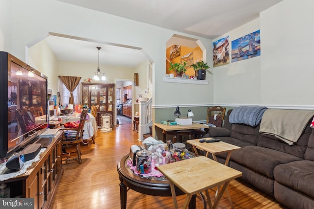 living room with stairs, hardwood / wood-style floors, and an inviting chandelier