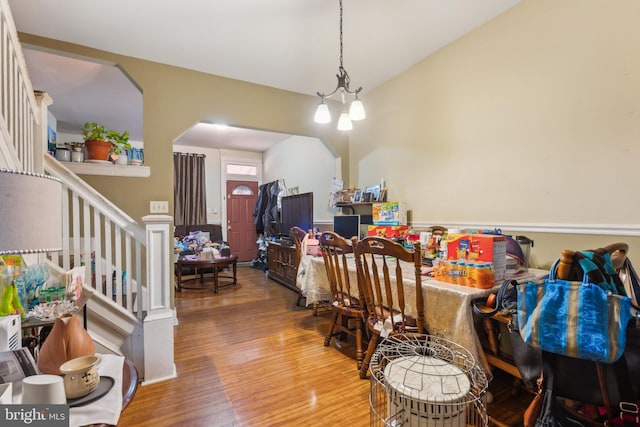 dining room featuring arched walkways, stairway, and wood finished floors