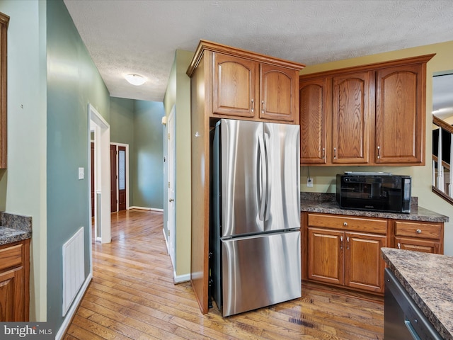 kitchen featuring stainless steel appliances, brown cabinetry, and light wood-style floors