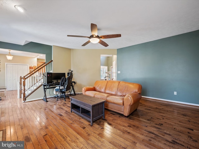 living area with wood-type flooring, ceiling fan, stairway, and baseboards