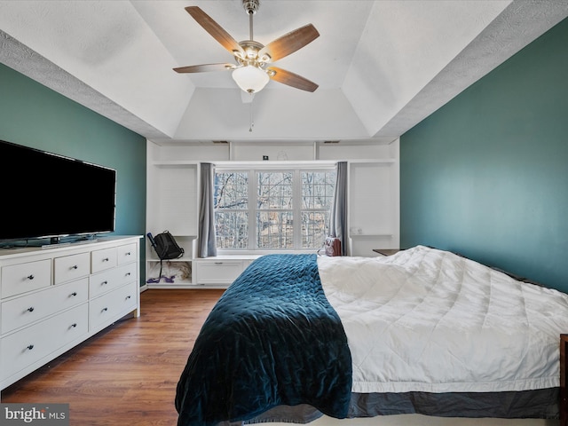 bedroom with a ceiling fan, lofted ceiling, and wood finished floors