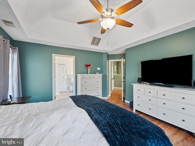 bedroom featuring wood finished floors, a raised ceiling, and visible vents