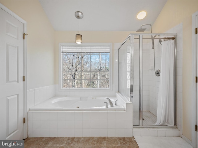 bathroom featuring a stall shower, a tub with jets, and vaulted ceiling