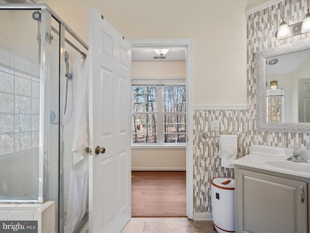 full bath with visible vents, vanity, a shower stall, and tile walls