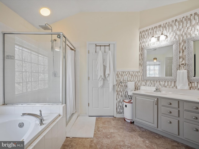 full bath with a stall shower, lofted ceiling, vanity, tiled tub, and tile walls