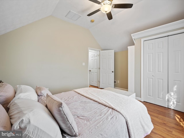 bedroom featuring visible vents, ceiling fan, wood finished floors, vaulted ceiling, and a closet