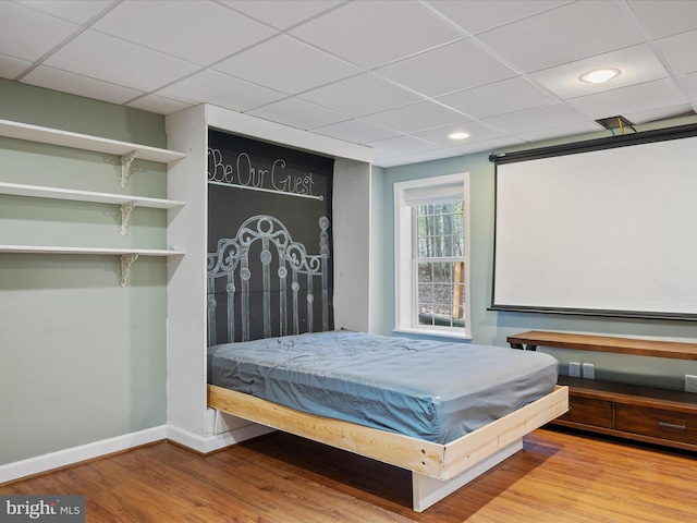 bedroom featuring a paneled ceiling, recessed lighting, baseboards, and wood finished floors