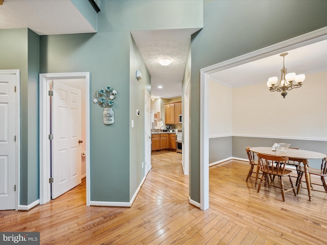 dining room with light wood-style flooring, baseboards, and a notable chandelier