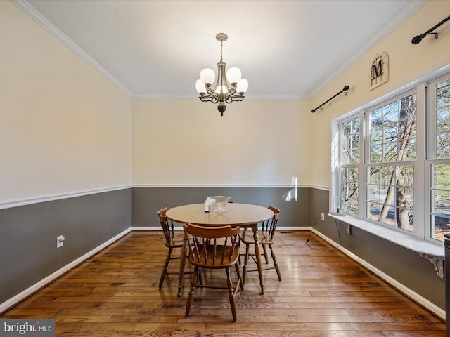 dining area with crown molding, hardwood / wood-style flooring, and a notable chandelier