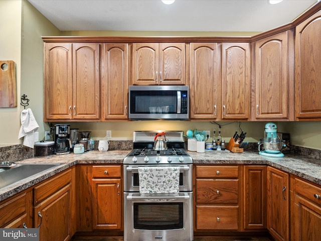 kitchen with stainless steel appliances, brown cabinetry, and a sink