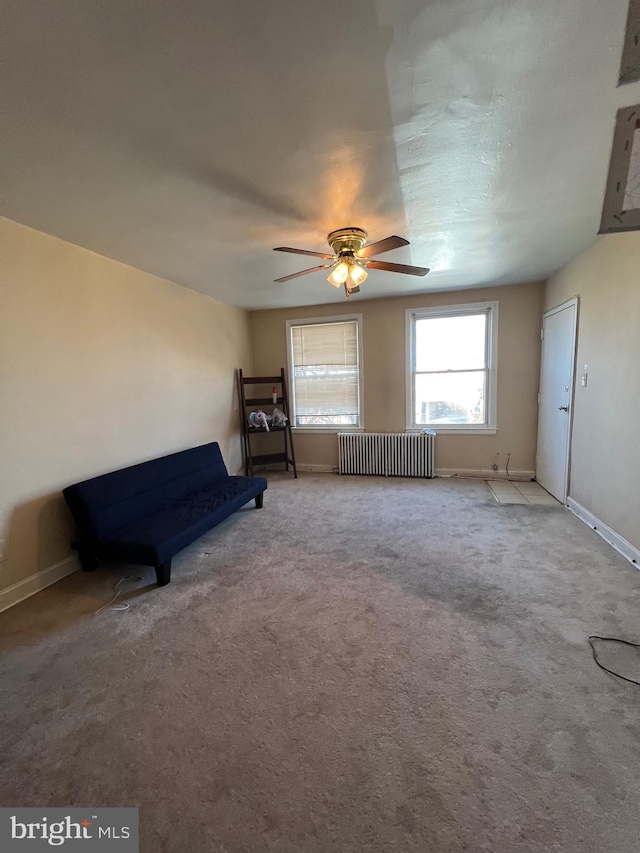 unfurnished room with carpet, radiator heating unit, baseboards, and a ceiling fan