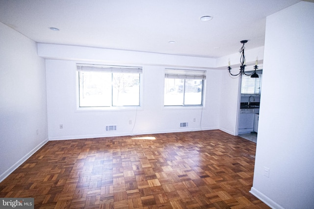 unfurnished dining area featuring an inviting chandelier, baseboards, visible vents, and a sink