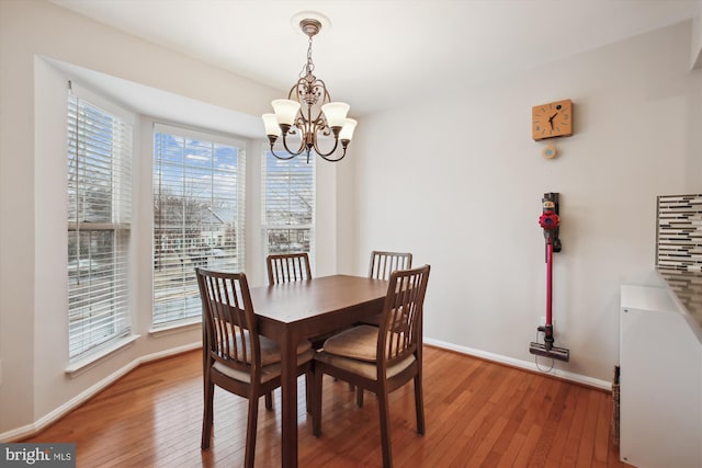 dining room with baseboards, light wood finished floors, and a notable chandelier