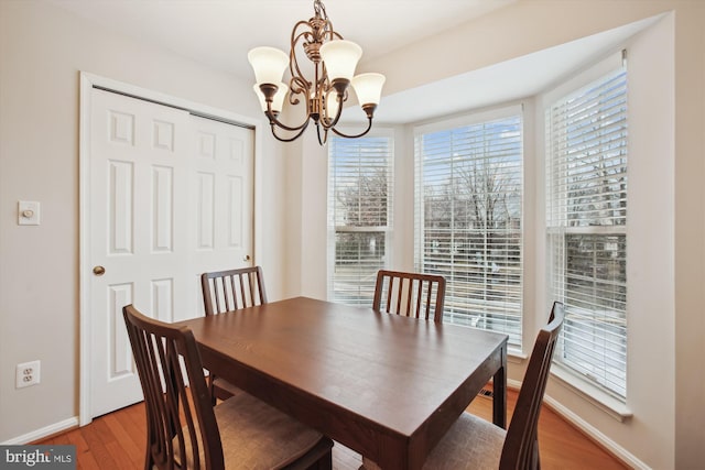 dining space with a chandelier, light wood-type flooring, and baseboards