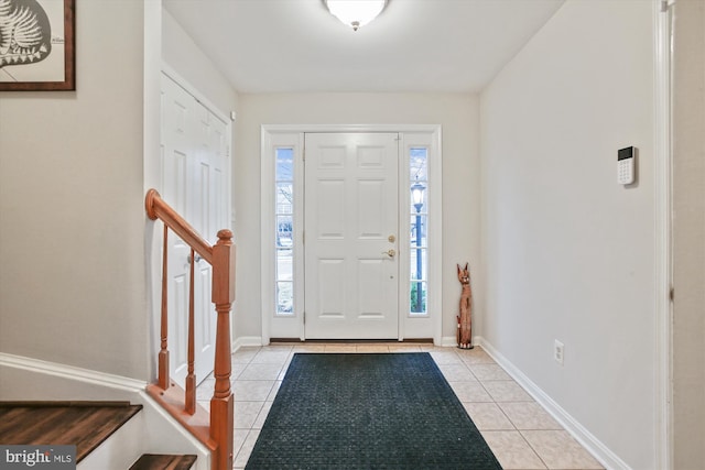 entryway featuring light tile patterned floors, stairs, and baseboards