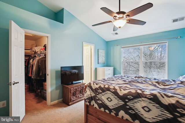 bedroom with light carpet, visible vents, a walk in closet, and lofted ceiling