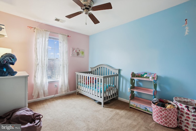 bedroom featuring carpet floors, a crib, visible vents, and baseboards