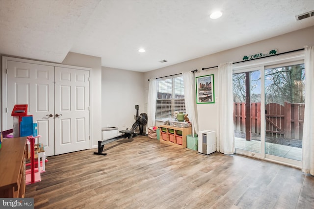 workout room featuring recessed lighting, visible vents, a textured ceiling, and wood finished floors