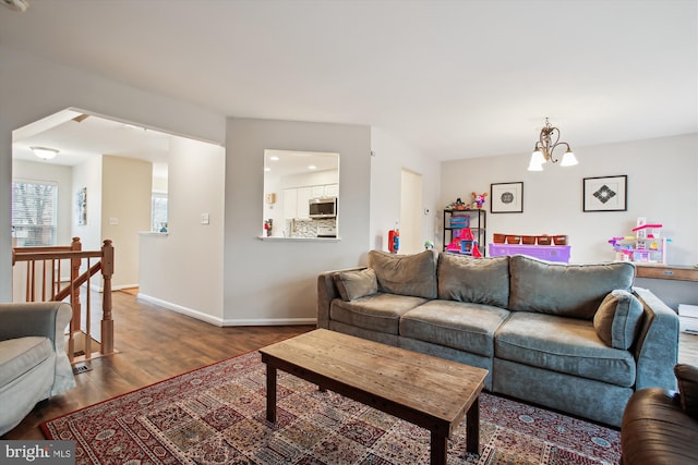 living area with a notable chandelier, baseboards, and wood finished floors