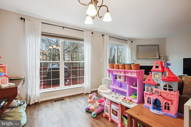 playroom with an inviting chandelier, baseboards, visible vents, and wood finished floors