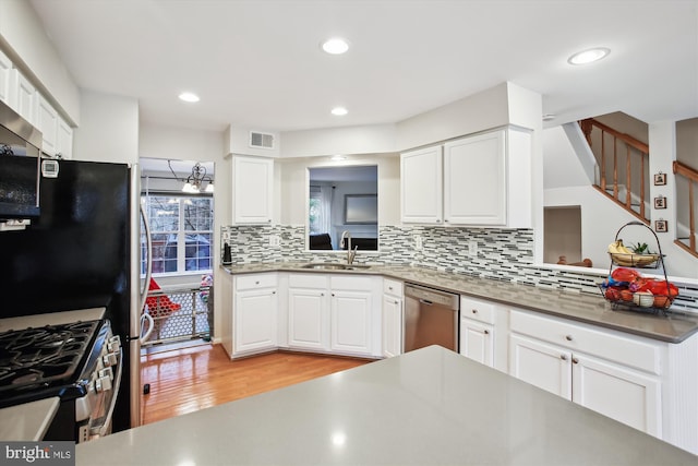 kitchen with tasteful backsplash, visible vents, appliances with stainless steel finishes, a sink, and light wood-type flooring