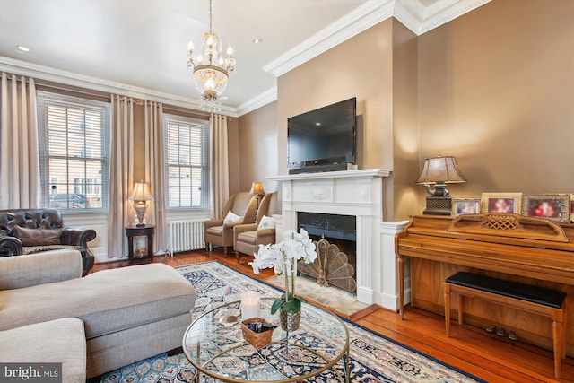 living area with a fireplace with flush hearth, a notable chandelier, wood-type flooring, radiator, and crown molding