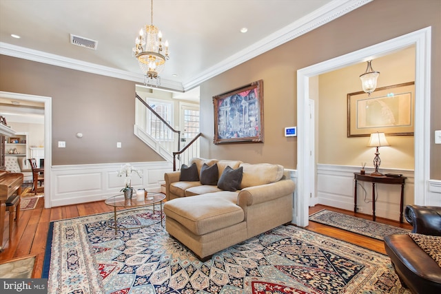 living area featuring visible vents, crown molding, stairs, hardwood / wood-style floors, and a notable chandelier