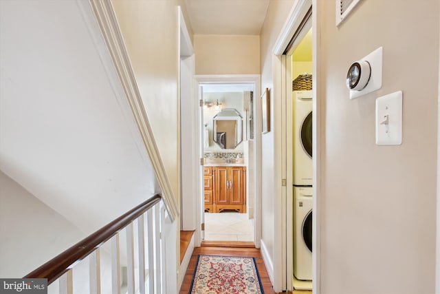 corridor featuring light wood-style flooring and stacked washer and dryer