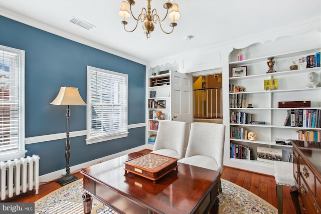 interior space with visible vents, baseboards, a chandelier, radiator heating unit, and wood finished floors