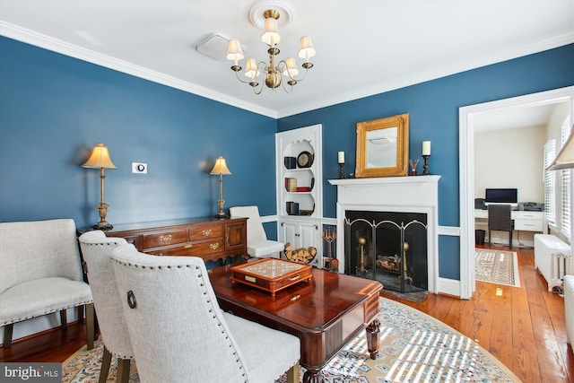 living area featuring a chandelier, a fireplace with flush hearth, radiator heating unit, ornamental molding, and hardwood / wood-style flooring