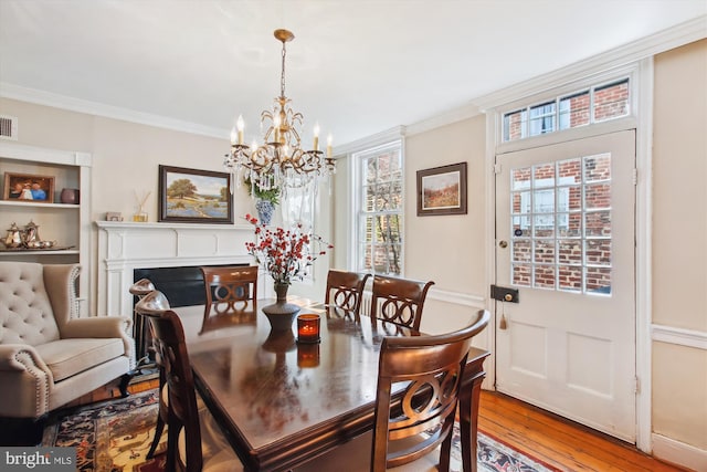 dining room with a notable chandelier, visible vents, hardwood / wood-style floors, and ornamental molding