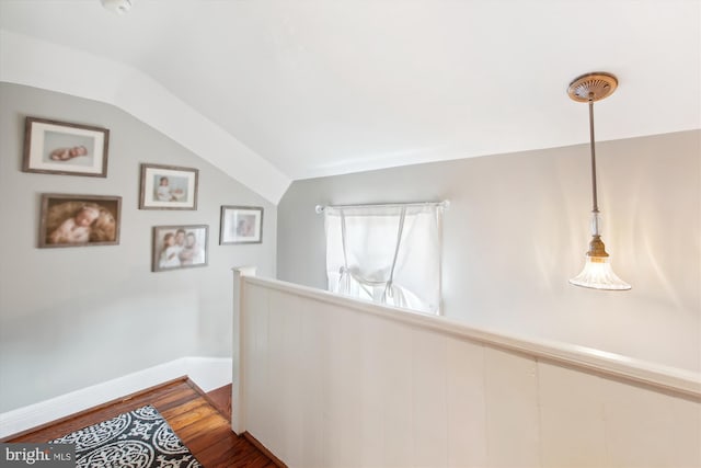 hall with wood finished floors, an upstairs landing, baseboards, and vaulted ceiling