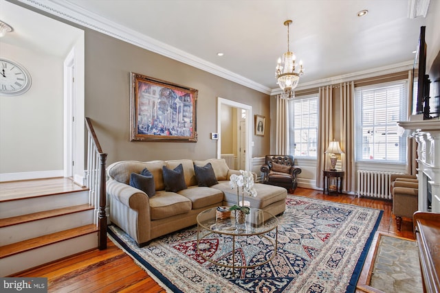 living room featuring a notable chandelier, ornamental molding, hardwood / wood-style floors, radiator heating unit, and stairway