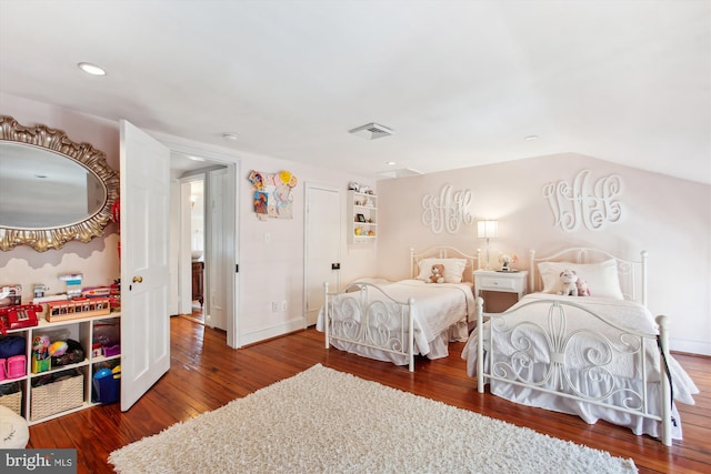 bedroom featuring visible vents, baseboards, lofted ceiling, and wood finished floors