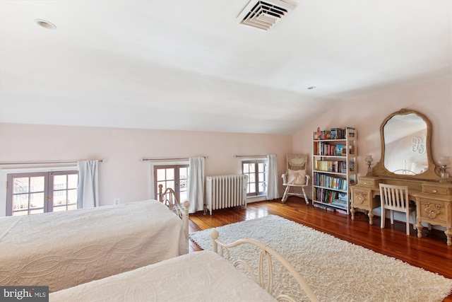 bedroom with wood finished floors, radiator, french doors, and visible vents