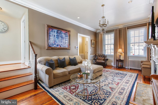 living room with radiator, an inviting chandelier, stairs, crown molding, and light wood-type flooring