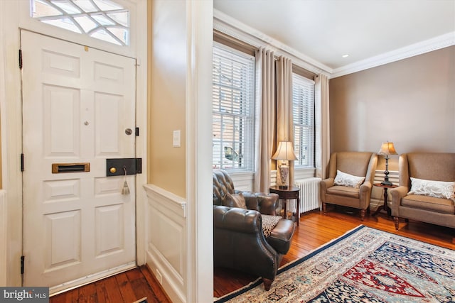 foyer entrance with dark wood-style floors, radiator, and crown molding