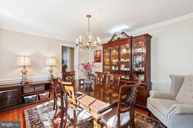 dining space with crown molding, wood finished floors, and a chandelier