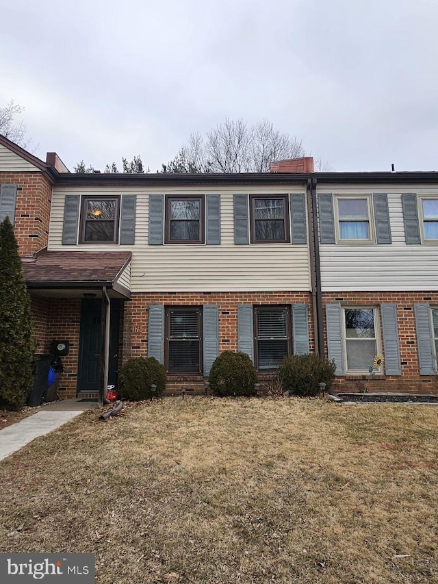 multi unit property with brick siding and a front yard