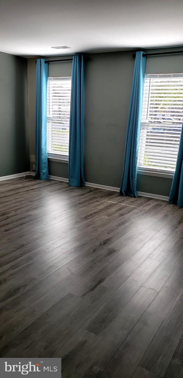 unfurnished room featuring baseboards and dark wood finished floors