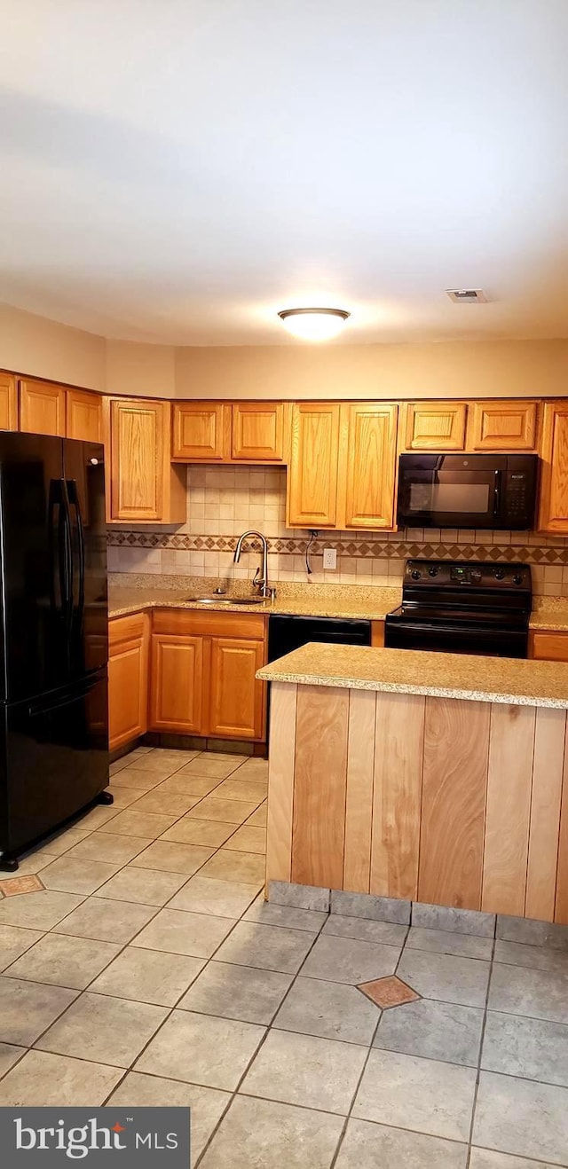 kitchen with light stone counters, visible vents, backsplash, a sink, and black appliances