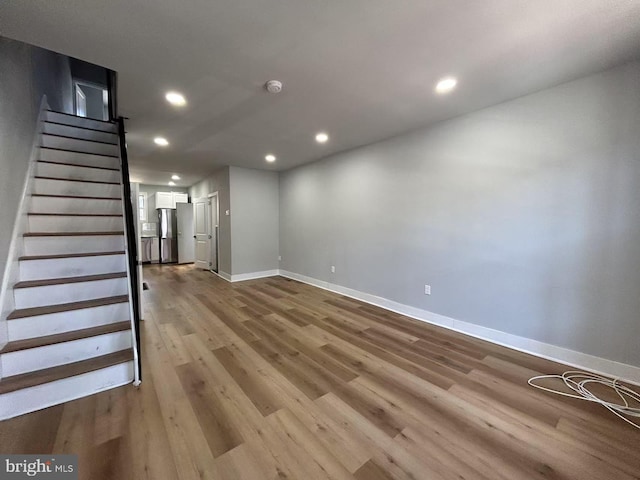 unfurnished living room featuring stairs, recessed lighting, wood finished floors, and baseboards