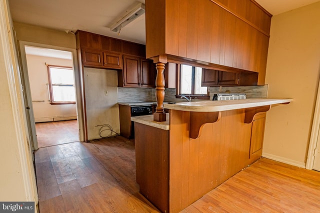 kitchen with a healthy amount of sunlight, light wood-style flooring, light countertops, and decorative backsplash