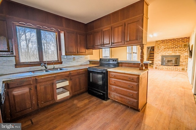 kitchen with dark wood-style flooring, a peninsula, light countertops, black range with electric cooktop, and a sink