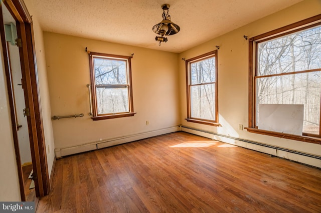 empty room with a healthy amount of sunlight, a textured ceiling, and wood finished floors