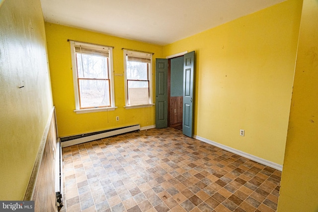 unfurnished bedroom featuring a baseboard heating unit and baseboards