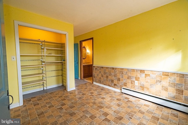 empty room featuring baseboards, a baseboard heating unit, and built in features