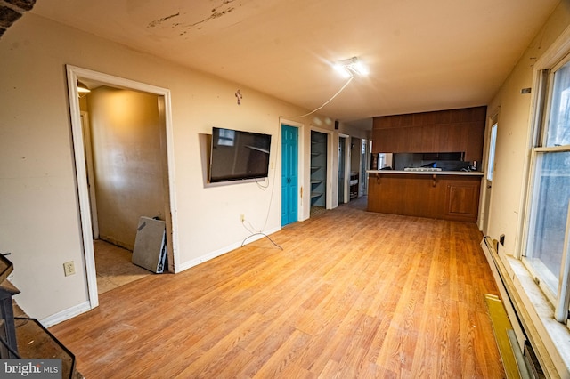 kitchen with brown cabinets, light wood finished floors, baseboard heating, and light countertops