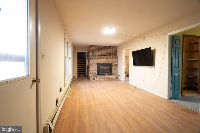 unfurnished living room with a fireplace, light wood finished floors, and baseboard heating