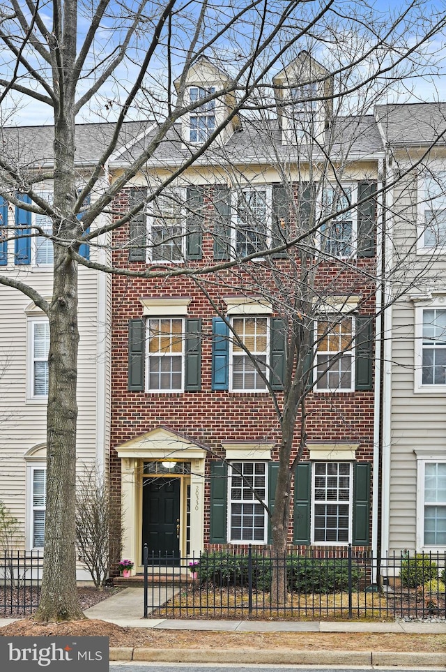 townhome / multi-family property with brick siding and a fenced front yard